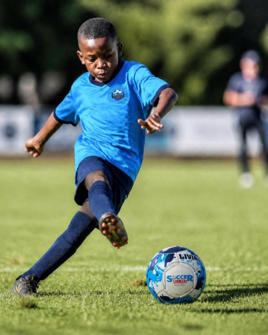 A boy in Soccer Strikers kit passing the ball